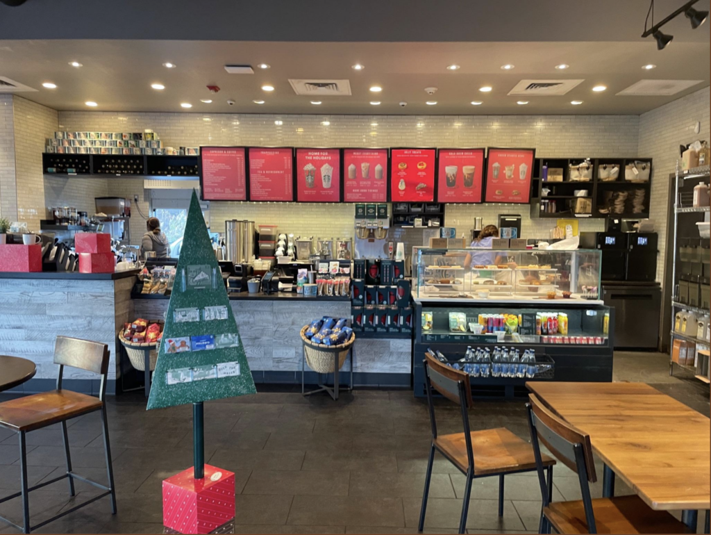 Interior of Starbucks, showing the counter to order and a tree that hold gift cards that also represents where to start the line to order